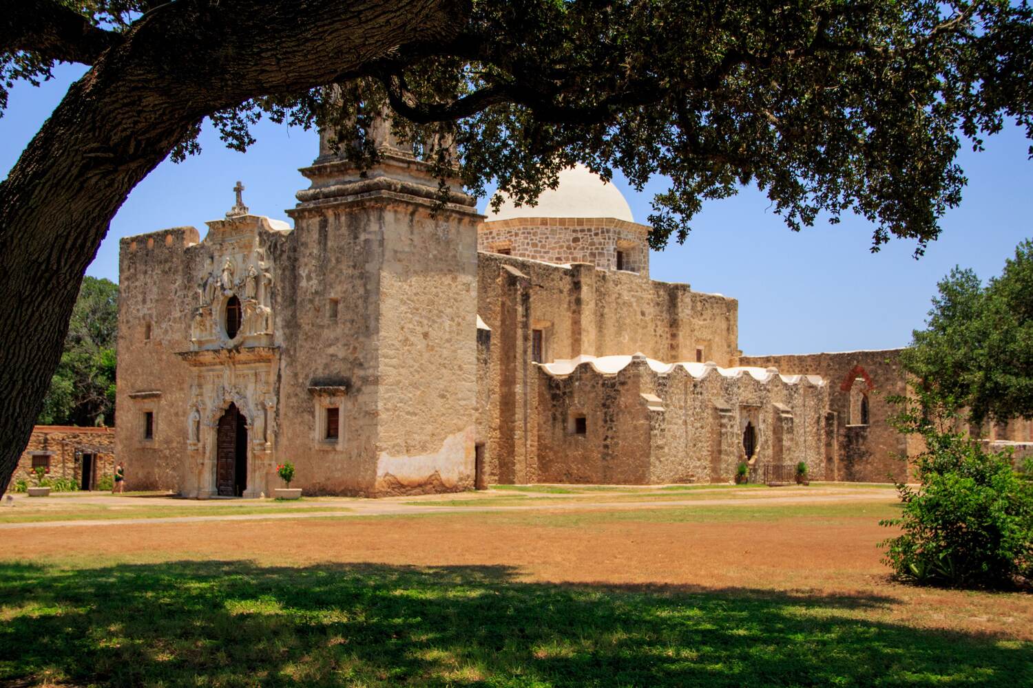 Mission San Jose facade framed by oak branches in San Antonio