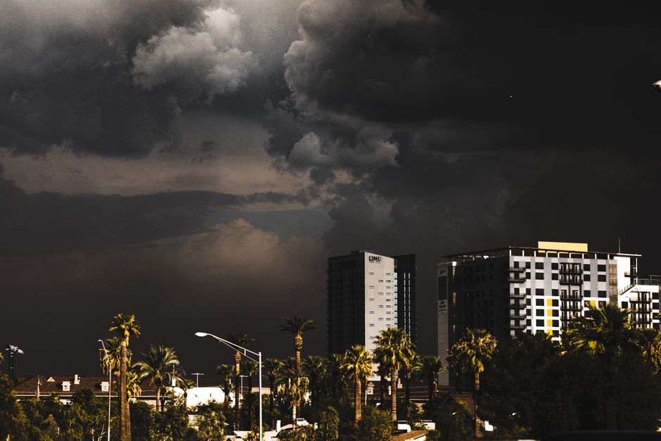 Dark storm clouds over city buildings and palm trees