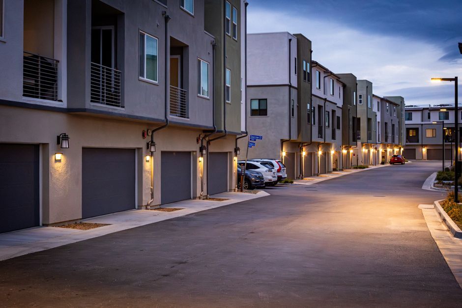 Row of townhome garages along a lamplit community drive at dusk